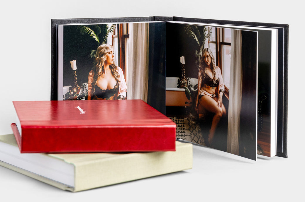 Three Boudoir 8x8" Album99, one book open to show a spread of Boudoir imagery. Covers featured: Pebbled Black Faux Leather, Cranberry Faux Leather, and Pistachio Linen