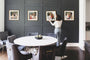 Dining room scene of a woman in front of a series of four 24x24" Gold, Thin Safari Framed Prints on a blue wall. 