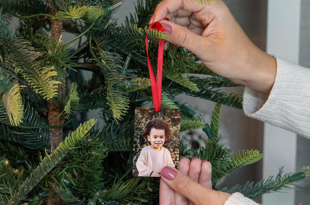 Woman holding a rectangle Metal Ornament and hanging it on a tree. 