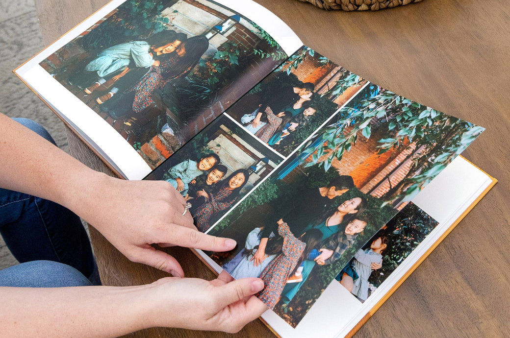 Woman looking at inside spread of Hardcover Photo Book with autumnal family.