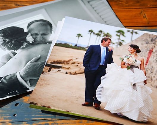 alt= The bride hugging her father on black and white print next to a 30x40 photo of the married couple on the beach  